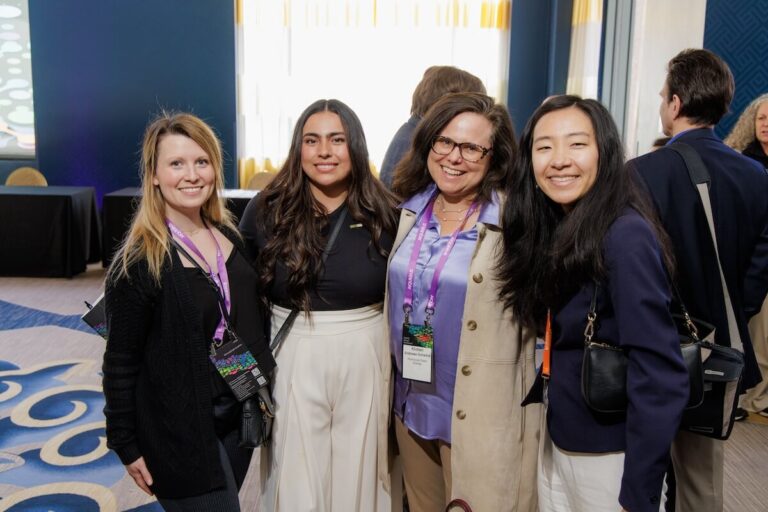 PCE staff smile for the camera while wearing lanyards at a conference