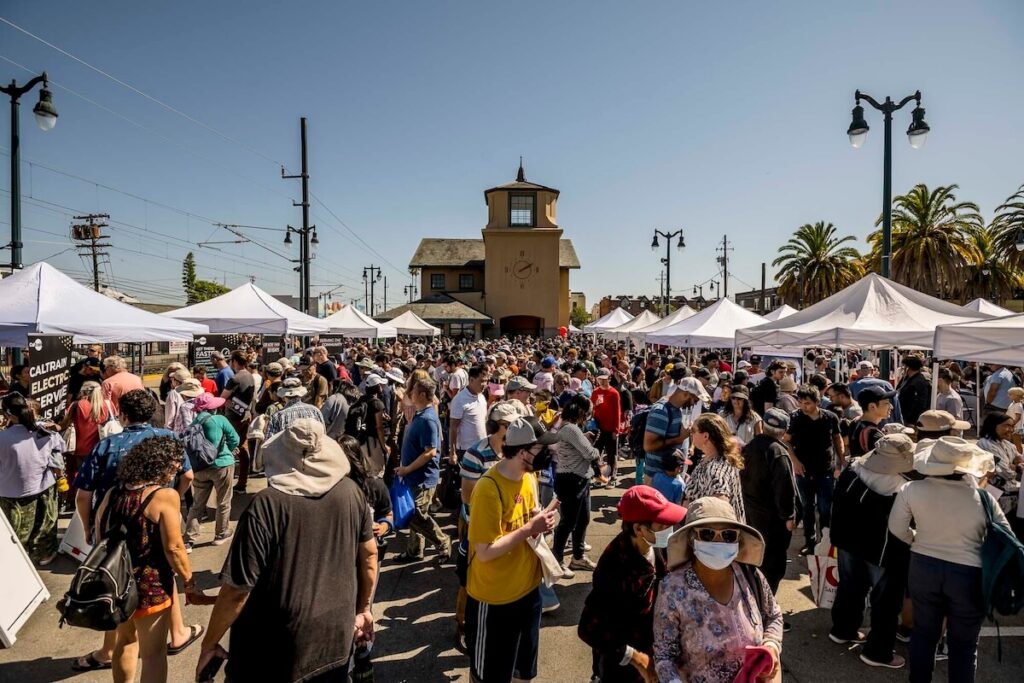 People gather at an outdoor farmers' market outside the San Mateo CalTrain station