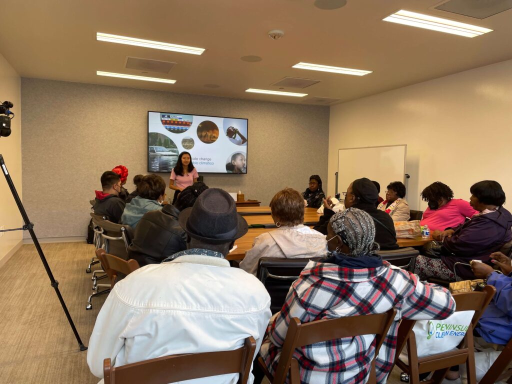 Vanessa Shin, Associate Manager of Community Relations at Peninsula Clean Energy, presenting to a group of community members in a classroom setting. The workshop focuses on supporting community-led energy change, with a slide displaying PCE initiatives in the background.