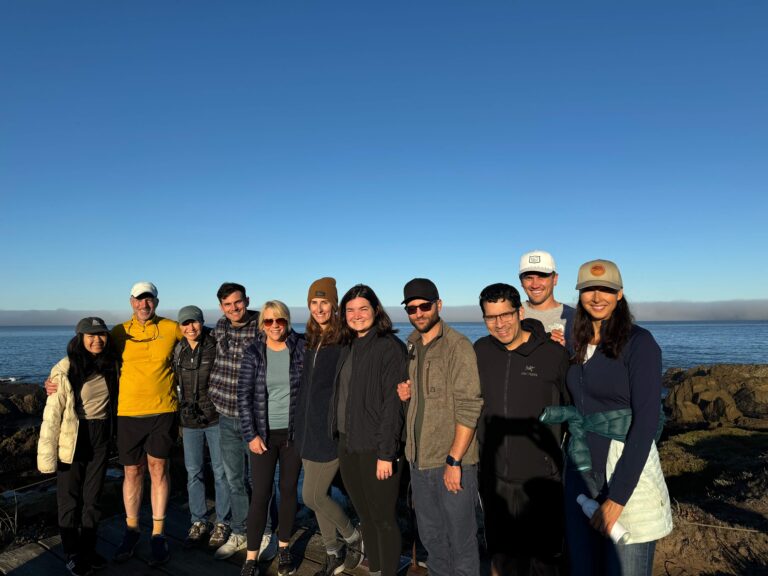 PCE staff smile for the camera while standing in front of an expansive, blue sky