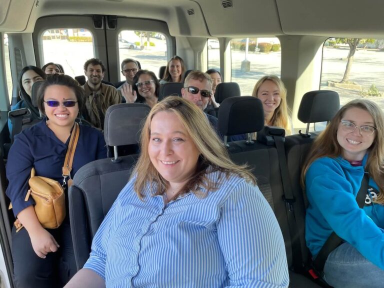 PCE staff members ride in a large van with multiple rows of people