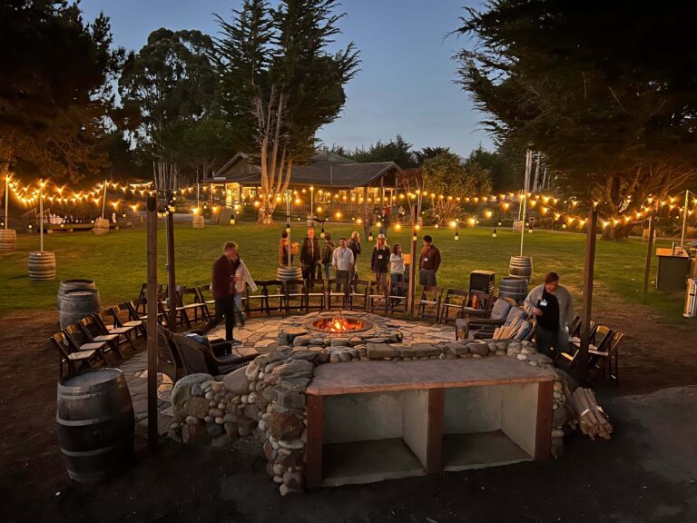 PCE staff gather around a fire pit at dusk during a retreat at Costanoa