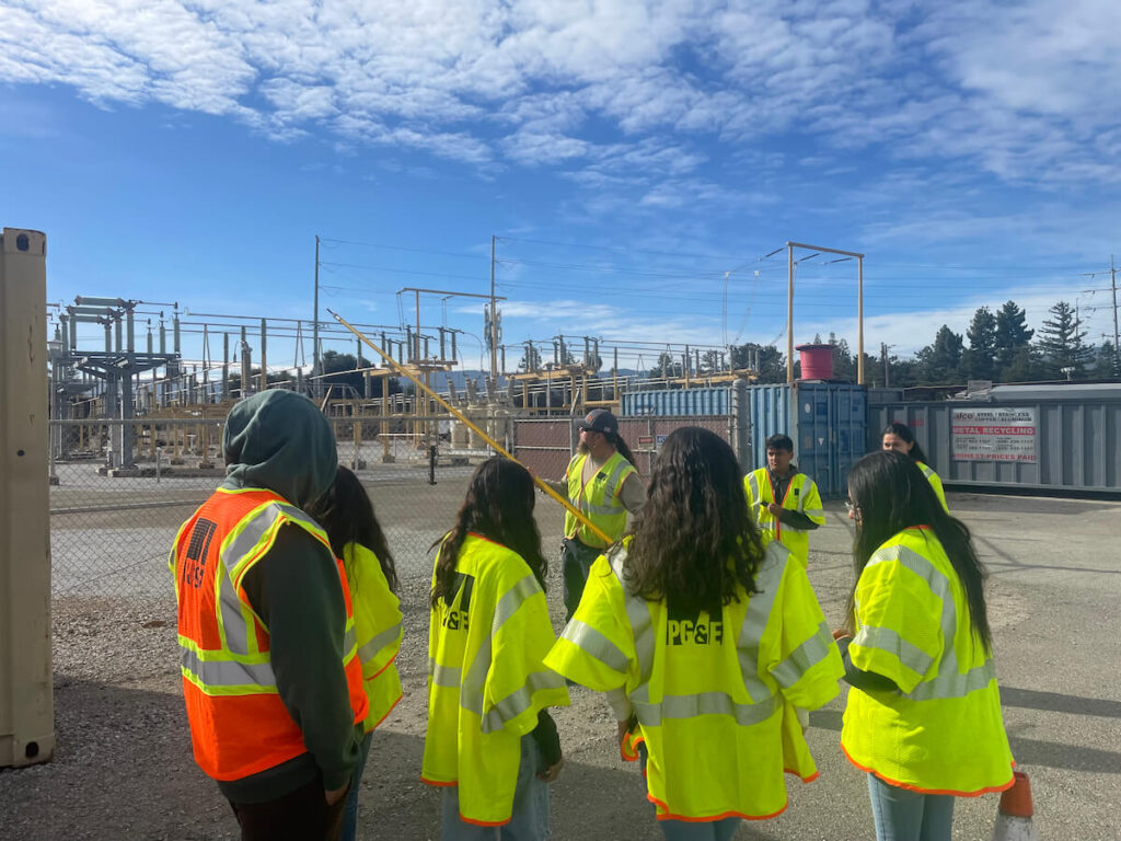 A group of students wear bright yellow vests as they learn about green career opportunities