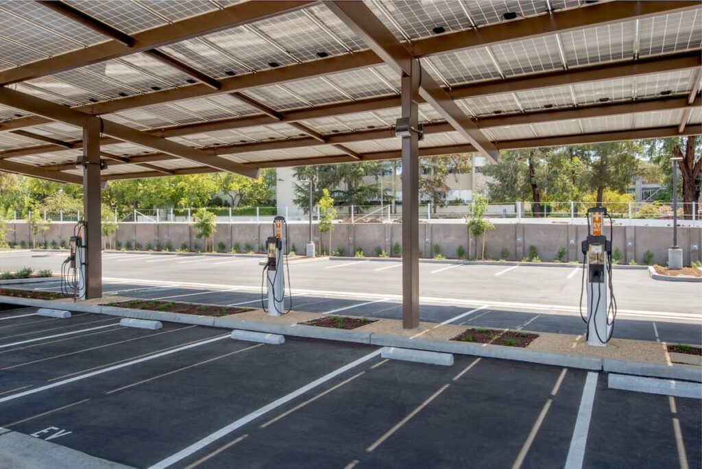 A covered parking lot has multiple EV charging stations