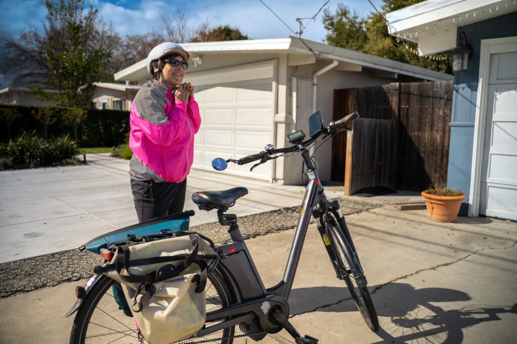 Woman with an electric bike in a residential driveway.